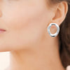 Boucles d'oreille Gina en acier PVD finition argent. Présentées portées.