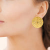 Boucles d'oreille Farah, disques 38mm martelés. En acier pvd doré. Présentées portées.