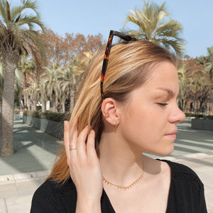 Photo portée de la bague Snake et de la bague d'oreille Snake, accessoirisant une petite robe noire d'été.